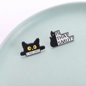 Set of two black enamel cat pins featuring Is That Smut humorous quotes on a ceramic tray