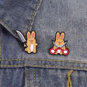 Set of two creative cartoon rabbit enamel pins with knife and scissors on denim fabric