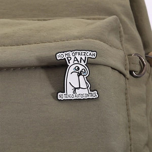 Detail view of Flork enamel pin with Spanish text pinned on an olive green canvas bag