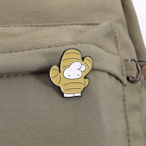 Detailed view of a creative yellow ginger enamel pin attached to an olive green bag
