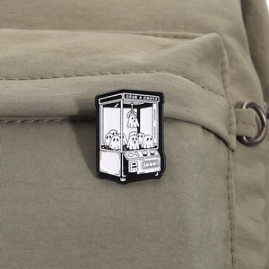Détail du pin's émaillé machine à fantômes sur la poche d'un sac à dos en toile verte