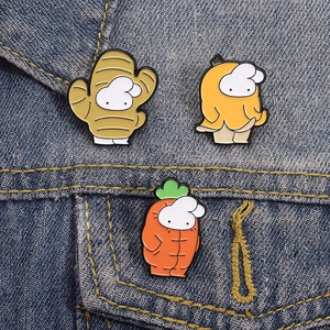 Set of three cute cartoon fruit and vegetable enamel pins styled on a blue denim jacket