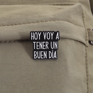 Close-up of enamel brooch with Spanish quote on khaki canvas backpack background