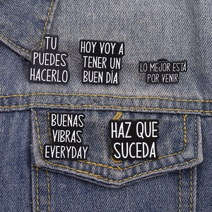 Close-up of black and white inspirational Spanish quote pins on blue denim fabric