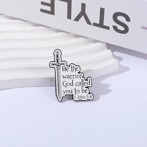 Enamel sword brooch with 1 John 5:4 scripture on a minimalist white display