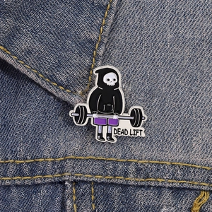 Cartoon skeleton lifting weights enamel pin badge on a denim jacket collar