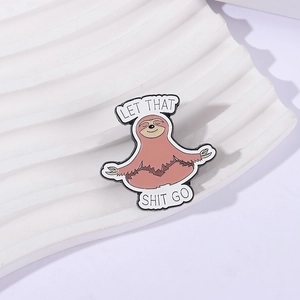 Cute enamel sloth meditation brooch pin with 'Let That Shit Go' text on white tray