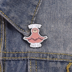 Funny pink sloth meditation enamel pin on denim jacket with Let That Shit Go text