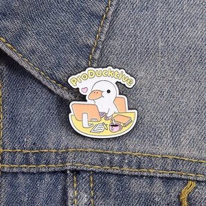 Macro shot of cartoon ProDucktive office duck enamel pin on dark blue denim fabric