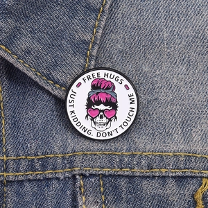 Détail macro du pin's émaillé squelette avec texte Free Hugs sur veste en jean