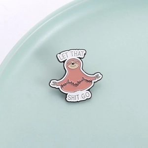 Cute cartoon yoga sloth enamel pin with 'Let That Shit Go' slogan on ceramic tray