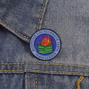 Detail of blue dumpster fire enamel pin on a denim jacket showing the response team logo