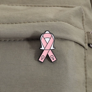 Détail de l'épinglette en émail ruban rose avec symboles de genre sur toile verte