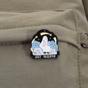 Detail of Just Observin ghost enamel pin attached to green canvas fabric material