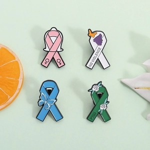 Set of four awareness ribbon metal pins featuring butterfly and floral themes on green surface