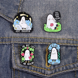 Set of four cute white enamel ghost pins with creative slogans on a denim jacket