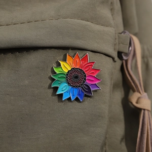 Rainbow sunflower enamel pin with colorful gradient petals on olive green canvas bag