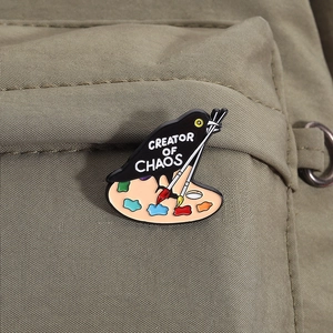 Detail der Creator of Chaos Emaille-Anstecknadel mit Vogel und Palette auf Stoff