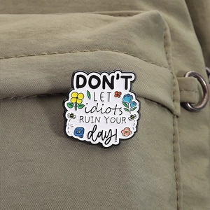 Détail d'une broche émaillée inspirante avec fleurs et abeille sur un sac en tissu olive