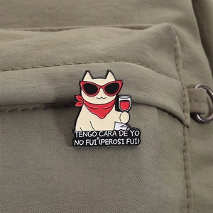 Detail of cartoon cat enamel pin with red sunglasses pinned on a green fabric bag