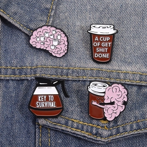 Macro detail of four enamel coffee-themed badges including brain and cup on denim
