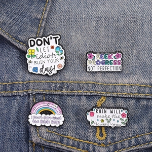 Lot de quatre pin's en émail fleuris et inspirants sur une veste en jean