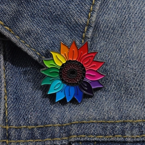 Détail d'un pin's émaillé tournesol arc-en-ciel sur le revers d'une veste en jean