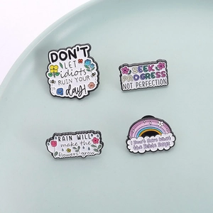 Lot de quatre pin's en émail colorés avec motifs floraux et citations motivantes sur plateau