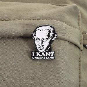 Detail of philosopher Kant enamel pin with I Kant Understand text on green canvas