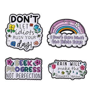 Lot de quatre broches en émail coloré avec motifs floraux, arc-en-ciel et citations motivantes