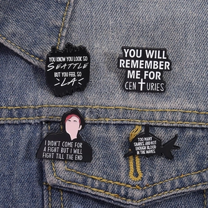Dettaglio delle spille Fall Out Boy in smalto con citazioni su tessuto denim blu