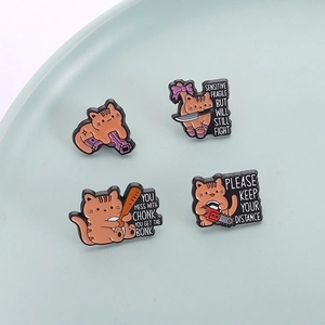 Set of four funny orange cat enamel pins with humorous quotes on a ceramic tray