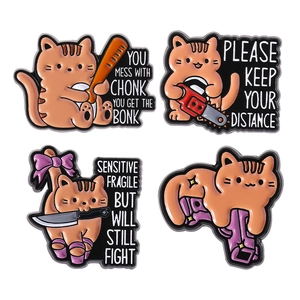 Funny set of four orange cat enamel pins with cartoon weapon designs and humor quotes
