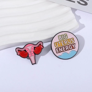 Empowering enamel pins set with pink uterus boxing gloves and Big Uterus Energy slogan