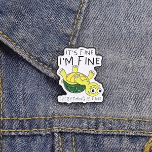 Detail einer lustigen Schildkröten-Emaille-Anstecknadel auf Jeansjacke mit Humor-Zitat