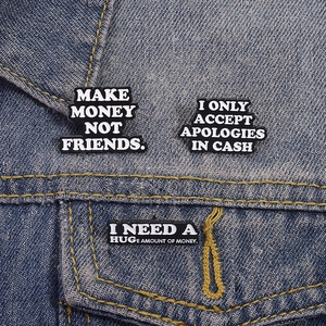 Trois broches en émail noir avec citations fixées sur une veste en jean bleu