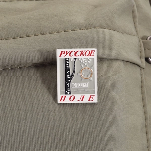 Macro detail of enamel pin featuring Russian birch tree design on green fabric background