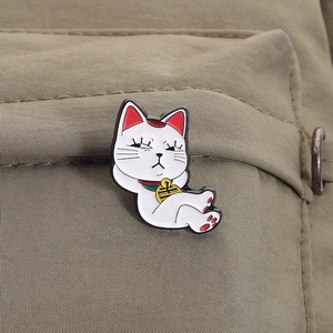 Vue détaillée d'un pin's chat porte-bonheur en émail sur un sac à dos en toile kaki