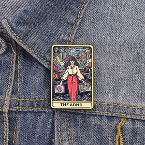 Pin's ADHD en émail style tarot avec design féminin sur une veste en jean bleu