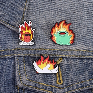 Cute cartoon enamel pins set featuring a flaming frog and spicy potato on denim fabric