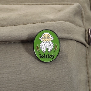 Detalle del pin esmaltado de León Tolstói con espigas sobre tela de lona caqui