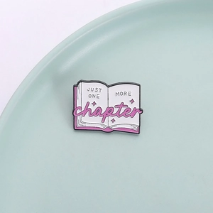 Pink and white enamel book brooch pin with Just One More Chapter quote on mint green plate