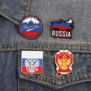 Detail of Russian eagle and cathedral enamel pins on blue denim jacket fabric