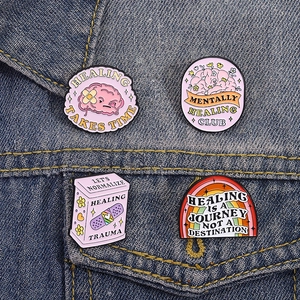 Mental health enamel pins set with healing quotes on dark denim jacket background