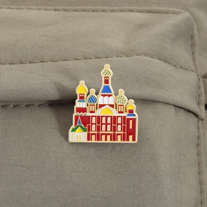 Macro detail of enamel Saint Basil's Cathedral brooch pinned on a beige nylon fabric surface