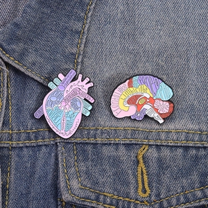 Anatomy enamel pins featuring brain and heart diagrams on blue denim jacket collar