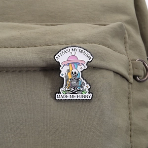 Close-up of a skull and UFO enamel pin attached to a green fabric backpack pocket