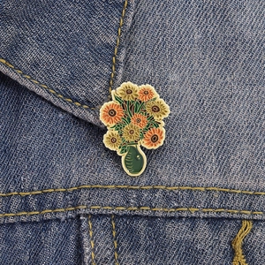 Emaille-Brosche im Ölgemälde-Stil mit Sonnenblumen-Motiv auf Jeansstoff gepinnt