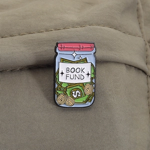 Detailed view of an enamel book fund jar pin featuring dollar bills and golden coins