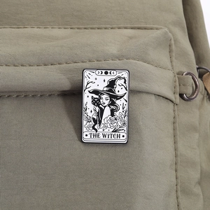 Detail of The Witch and cat enamel pin featuring tarot style on a green backpack